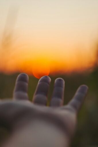 Hand reaching into sunset by Alexei Scutari